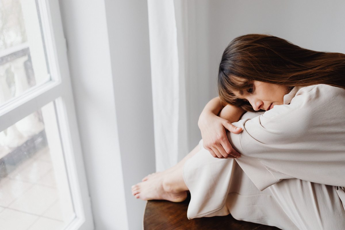 Mulher junto à janela em momento introspetivo — dor pélvica e intimidade